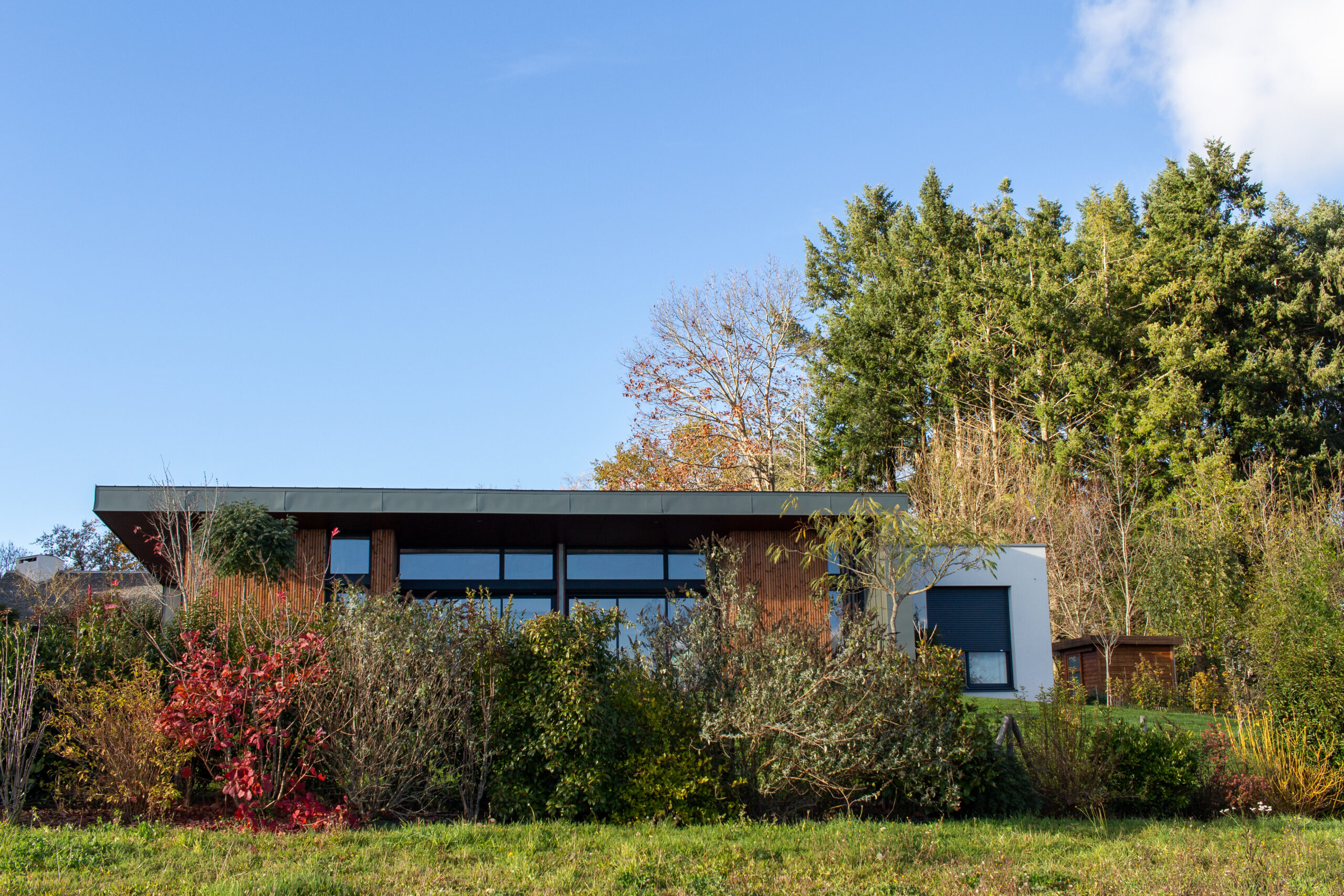 Maison d'architecte à Rodez (Olemps), conçue pour s'intégrer harmonieusement à son environnement naturel grâce à l'utilisation élégante de bois et de zinc vert. Cette réalisation illustre le savoir-faire de l'agence, qui privilégie des matériaux durables et une architecture respectueuse du paysage.